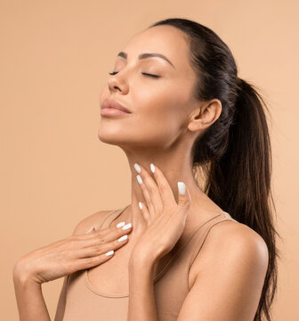 Sensual woman touching her neck and chest with eyes closed