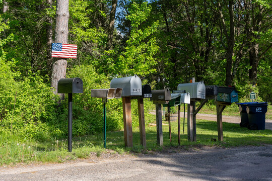 Row of Rural Mailboxes Beside Gravel Road With American Flag
