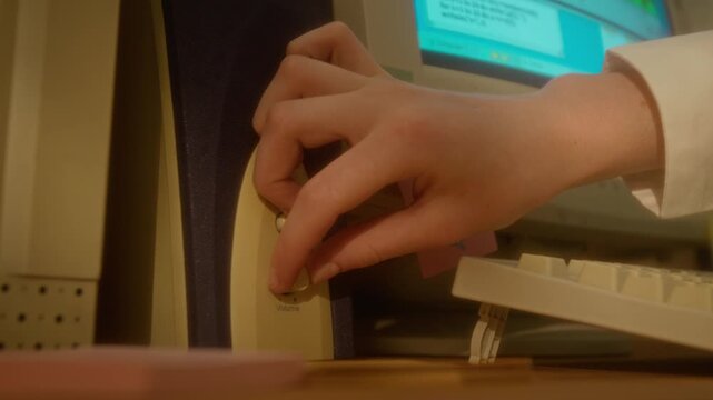 Unrecognizable teenagers hand reaching out to adjust volume knob on retro computer speaker next to CRT monitor. Footage is perfect for retro technology documentaries and nostalgia marketing campaigns