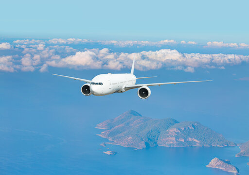 White airplane flying over green island and tropical sea - Travel Destinations Concept