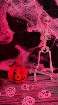 Red lit Halloween skeleton with pumpkin, skulls and spooky cobwebs