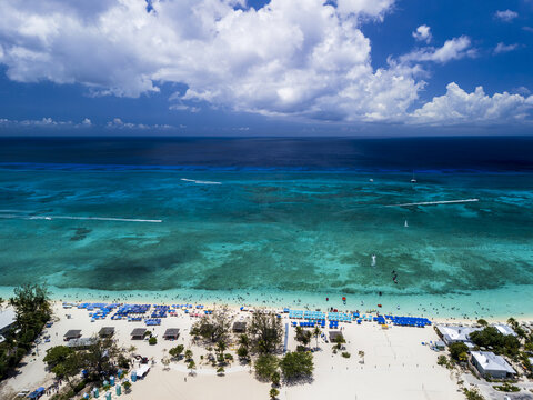 Aerial view of Seven Mile Beach with turquoise waters, white sand, and beach umbrellas on the coast of Grand Cayman, Cayman Islands.