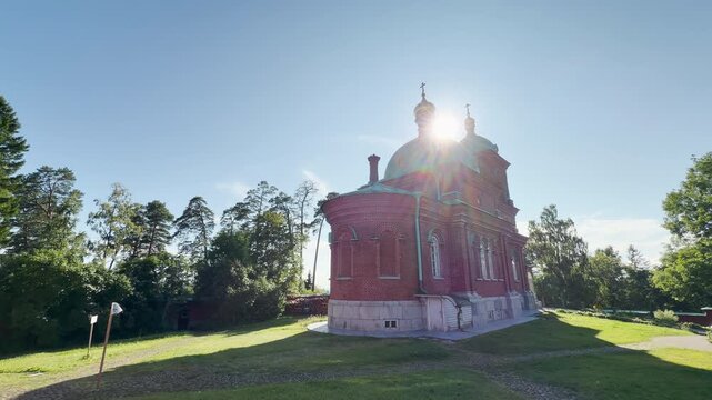The Resurrection Skete stands under bright sunlight. This sacred red brick church rests peacefully in Valaam, Lake Ladoga, inspiring a serene, awe-inspiring feeling of calm and spiritual beauty.