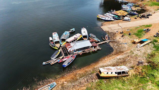 Aerial view of Jangari reservoir with numerous colorful wooden boats moored around a floating structure in Cianjur, West Java, Indonesia.