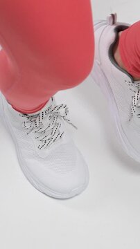 [Slow Motion] A vertical, overhead shot of a woman's feet as she does fitness exercises, moving nimbly in her athletic shoes
