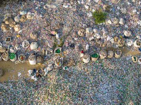 Aerial view of the plastic waste recycling site in Bakalia with workers sorting plastic bottles into large white sacks amidst scattered debris in Chattogram, Chittagong Division, Bangladesh.