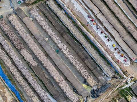 Aerial view of fish drying racks in Bakalia with workers processing fish on long bamboo mats in Chattogram, Chittagong Division, Bangladesh.