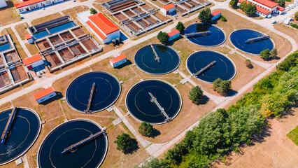 Naklejka premium Water treatment facility shown from above with round tanks and buildings. The image shows a water treatment facility with large round tanks and several buildings. The tanks are arranged neatly.