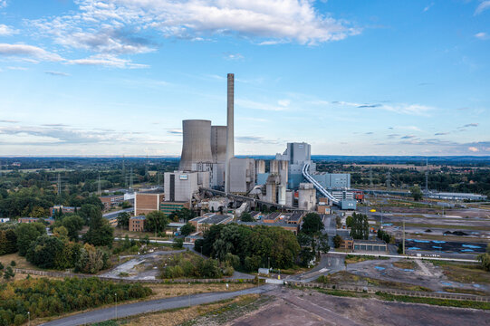 Aerial view of RWE Westfalen power plant with its cooling towers and tall chimney set against a blue sky with scattered clouds in Hamm, Nordrhein-Westfalen, Germany.