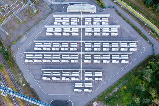 Aerial view of the RWE Westfalen battery storage facility with rows of white containers on a paved site surrounded by greenery and railway tracks in Hamm, Nordrhein-Westfalen, Germany.