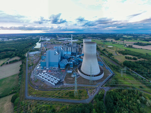 Aerial view of the RWE Westfalen power plant with its large cooling towers and industrial buildings surrounded by green fields and trees in Hamm, Nordrhein-Westfalen, Germany.