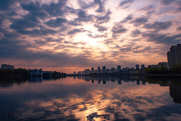 Fototapeta premium Urban lakeside park dusk scenery, buildings reflection on lake water