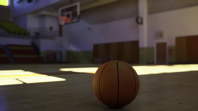 Awaiting shot on quiet court. Unoccupied gym with focused player ready. Silent gym setting with basketball waiting in warm sunlight for action
