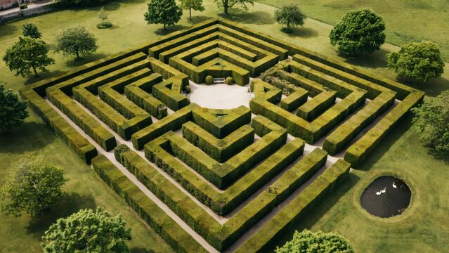 Aerial view of a square hedge maze with a central clearing and a small pond nearby with space benches surrounded