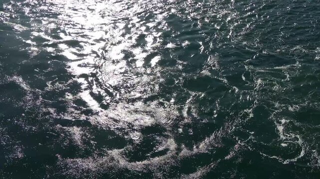Dark ocean water surface with sun reflection