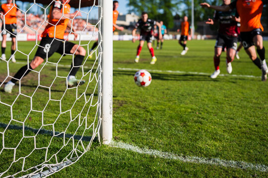 Action on the Soccer Pitch With Players in Motion Seen Through a Stadium Goal Net and Focusing on the net