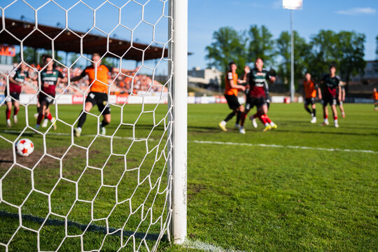 Action on the Soccer Pitch With Players in Motion Seen Through a Stadium Goal Net and Focusing on the goalpost.