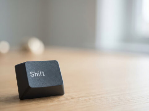 Shift key on wooden surface with blurred background, symbolizing technology and typing concept