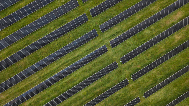 Aerial view of rows of solar panels installed on a green grassy field in Spain.