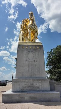 Vertical tilt up view of the newly gilded Sacrifice sculpture at Arlington Memorial Bridge in Washington, DC, gleaming against a blue sky. 15354  