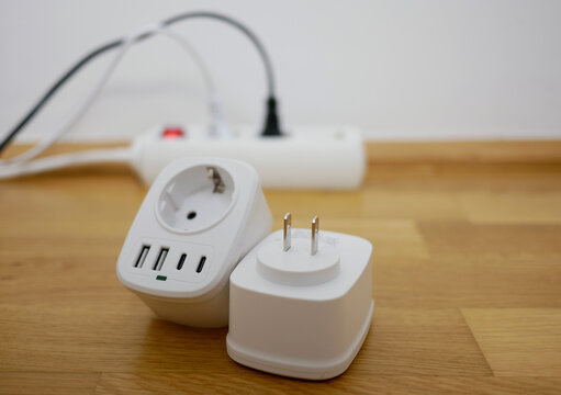 Universal travel adapter close up against the backdrop of a socket. Electric plug adapter, international plug socket gadget for travel.