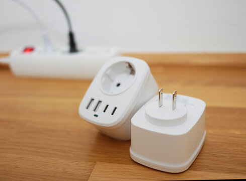 Universal travel adapter close up against the backdrop of a socket. Electric plug adapter, international plug socket gadget for travel.