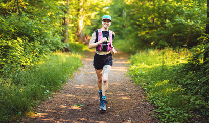 Fototapeta premium Young woman track suit running on the forest trail on summer