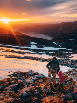 Father and child climbing sunset mountains together in Norway family extreme vacations travel outdoors, parent and child hiking with backpack gear, mountaineering tour active lifestyle hobby
