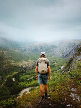 Man with backpack hiking solo in Rago park tourist travel in Norway, traveler explore remote wilderness on summer trekking adventure freedom endurance healthy lifestyle enjoying wild nature foggy view
