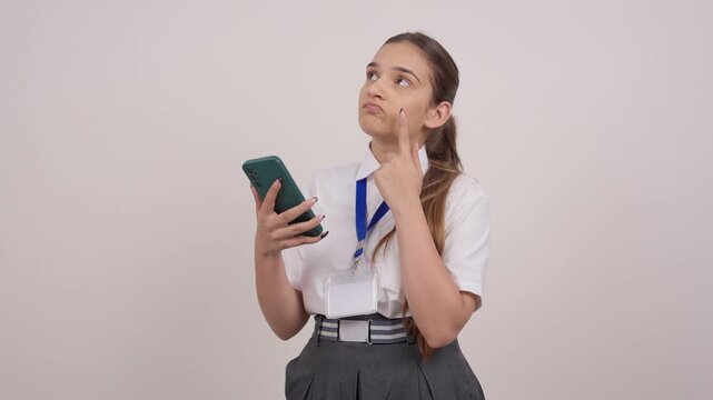 Indian Schoolgirl Looking at Phone and thinking