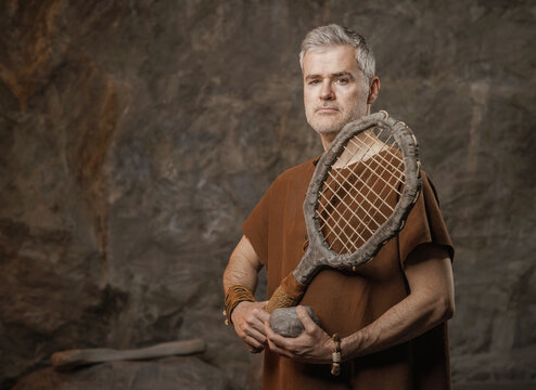 Funny Prehistoric Tennis Player with Stone Racket and Ball in a Cave