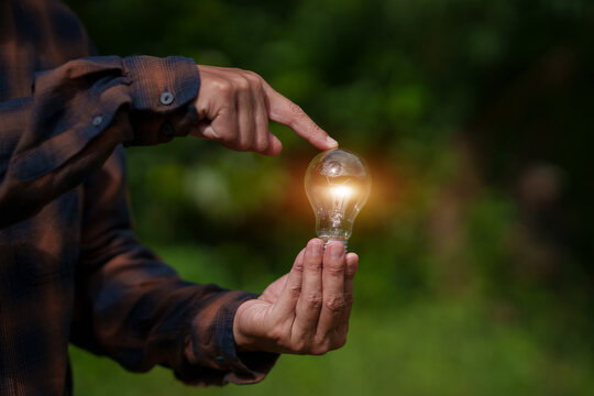 Farmer Holding Glowing Light Bulb for Green Energy and Sustainable Agricultural Innovation Concept