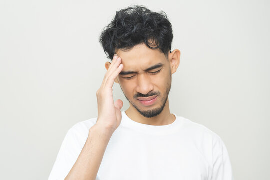 Dizzy asian young man, male headache or migraine pain suffering from vertigo or sick, holding head with hand, health problem of brain or inner ear not balance, standing isolated on white background.