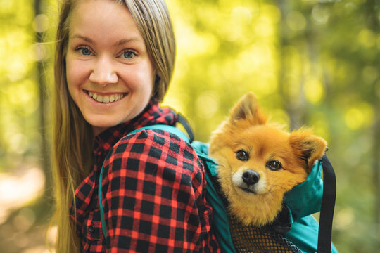 woman trekking in the forest. Traveling activity with her dog on backpack