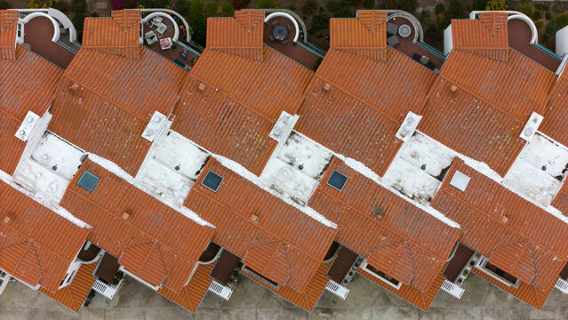 Aerial view of a residential complex featuring rows of terracotta-tiled roofs, white flat roof sections, skylights, and balconies in Morro Bay, California, United States.