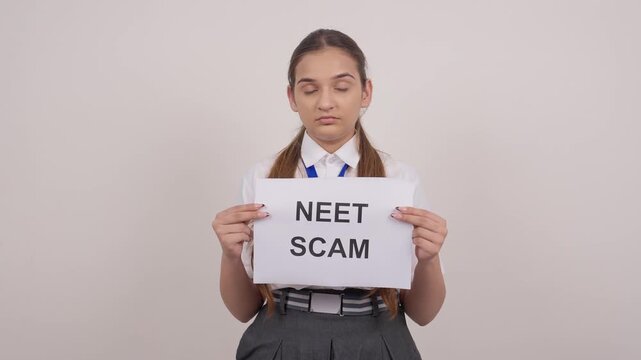 Schoolgirl Standing with NEET SCAM Poster
