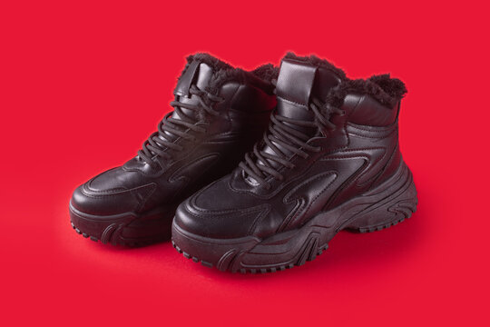 Leather classical sport shoes with fur isolated on red background. Winter high lace-up boots.