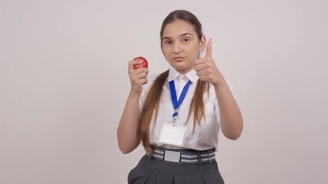 Indian Schoolgirl Eating Apple and Showing Thumbs Up