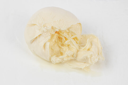 Fresh burrata cheese ball with creamy interior and torn outer shell placed on a white background, showcasing its rich texture and appearance