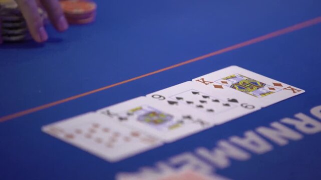 Poker dealer placing king of diamonds on blue felt table during tournament.