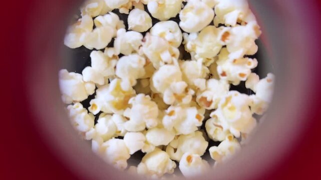 A captivating close up view of freshly popped popcorn falling into a vibrant red container creating a dynamic and appetizing visual.
