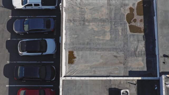 Aerial drone view above flat industrial retail business building rooftop and even roof with canvas having water damage from heavy rain and rainfall causing leaks and tears on roof's top with flooding