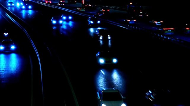 Night traffic flowing along a busy urban highway with bright headlights reflecting on the road, capturing city transportation, commuting and metropolitan mobility