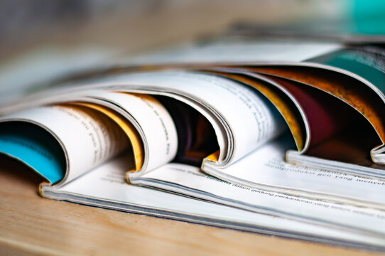 Stacked Glossy Magazines Open On A Wooden Desk Showing Curled Pages And Editorial Layouts For Design