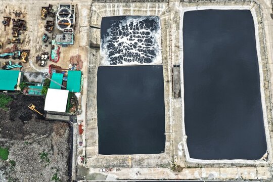 Aerial view of Aminbazar Landfill featuring large wastewater treatment ponds with dark water and aeration equipment in Aminbazar, Dhaka Division, Bangladesh.