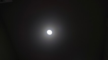 A single bright white light glowing in the center of a dark background. © Kelvin