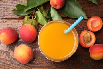 Apricot juice in glass, fresh fruits and leaves on wooden table, flat lay © New Africa