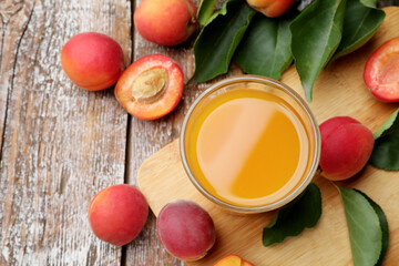 Apricot juice in glass, fresh fruits and leaves on wooden table, flat lay © New Africa