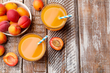 Apricot juice in glasses and fresh fruits on wooden table, flat lay. Space for text © New Africa