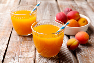 Apricot juice in glasses and fresh fruits on wooden table, closeup © New Africa